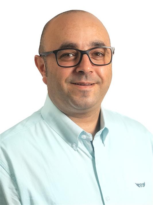 Foto do tronco de um homem de meia-idade com óculos e camisa azul