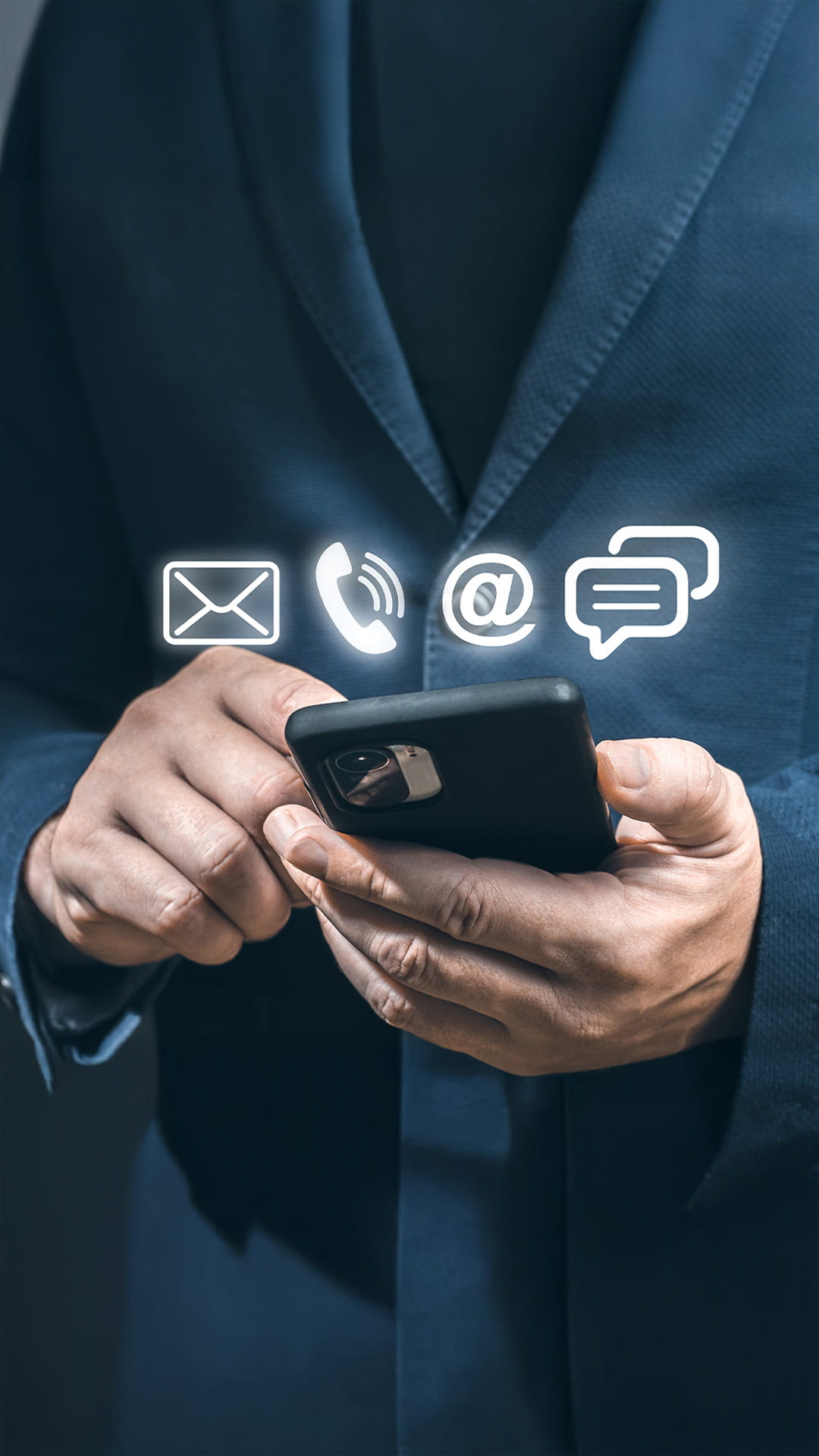 Personne tenant un smartphone avec des icônes de contact numériques lumineuses : e-mail, téléphone, arobase et bulle de chat.