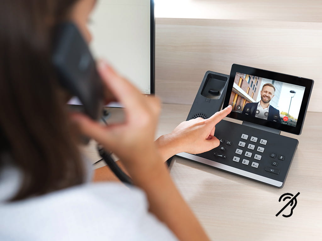 Vrouw aan een telefoongesprek met een bureau video-intercom die een man op het scherm toont.