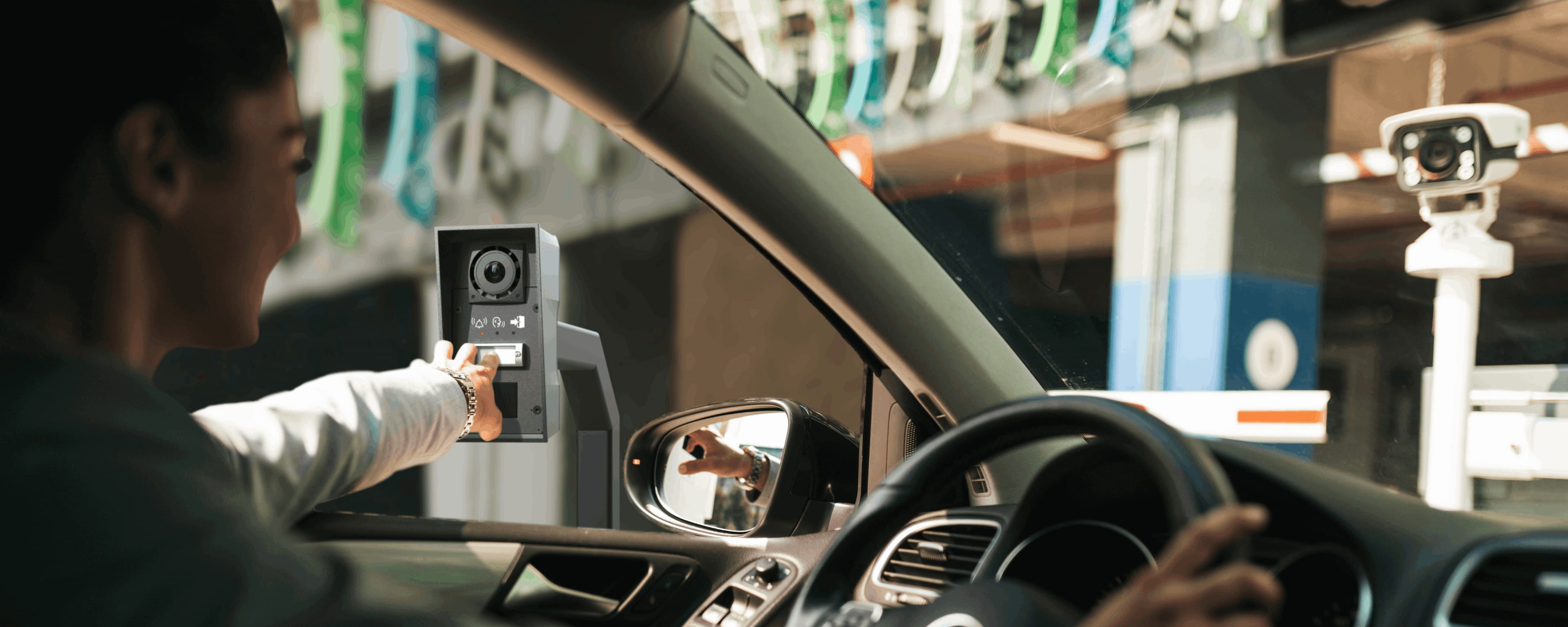 Vrouw in een auto die op een knop drukt op een intercom bij de ingang van een parkeergarage.