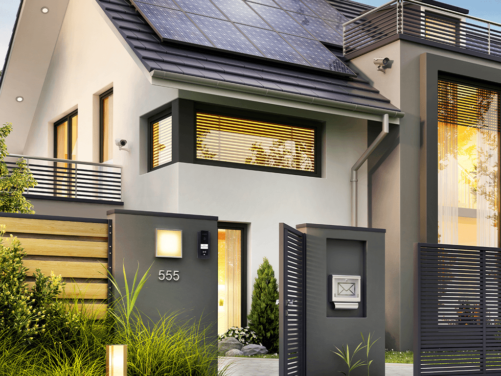 Modern house entrance with a gate, mailbox column, and wall-mounted video intercom beside a landscaped pathway.