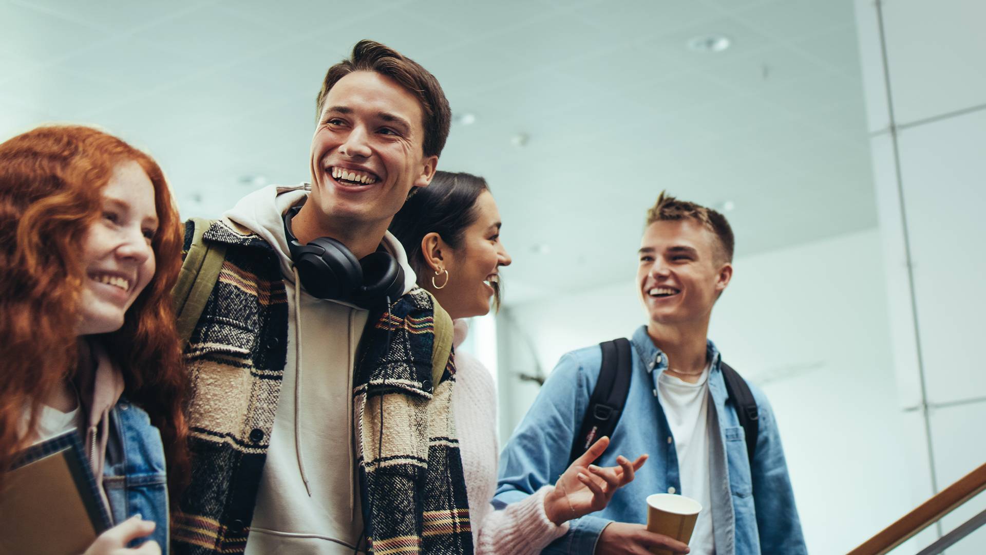 Quatre jeunes gens souriant, parlant et montant les escaliers