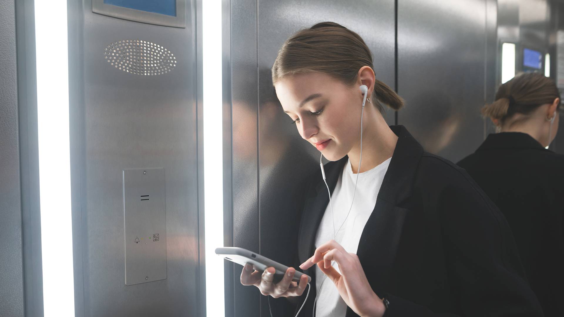 Fille dans l'ascenseur se sentant en sécurité avec le téléphone d'urgence 2N Lift