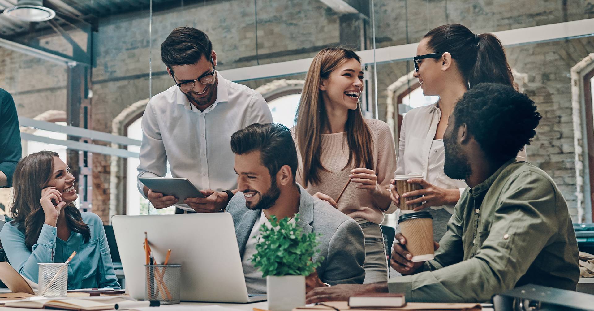 Seis colegas de trabalho sorridentes sentados a discutir o trabalho