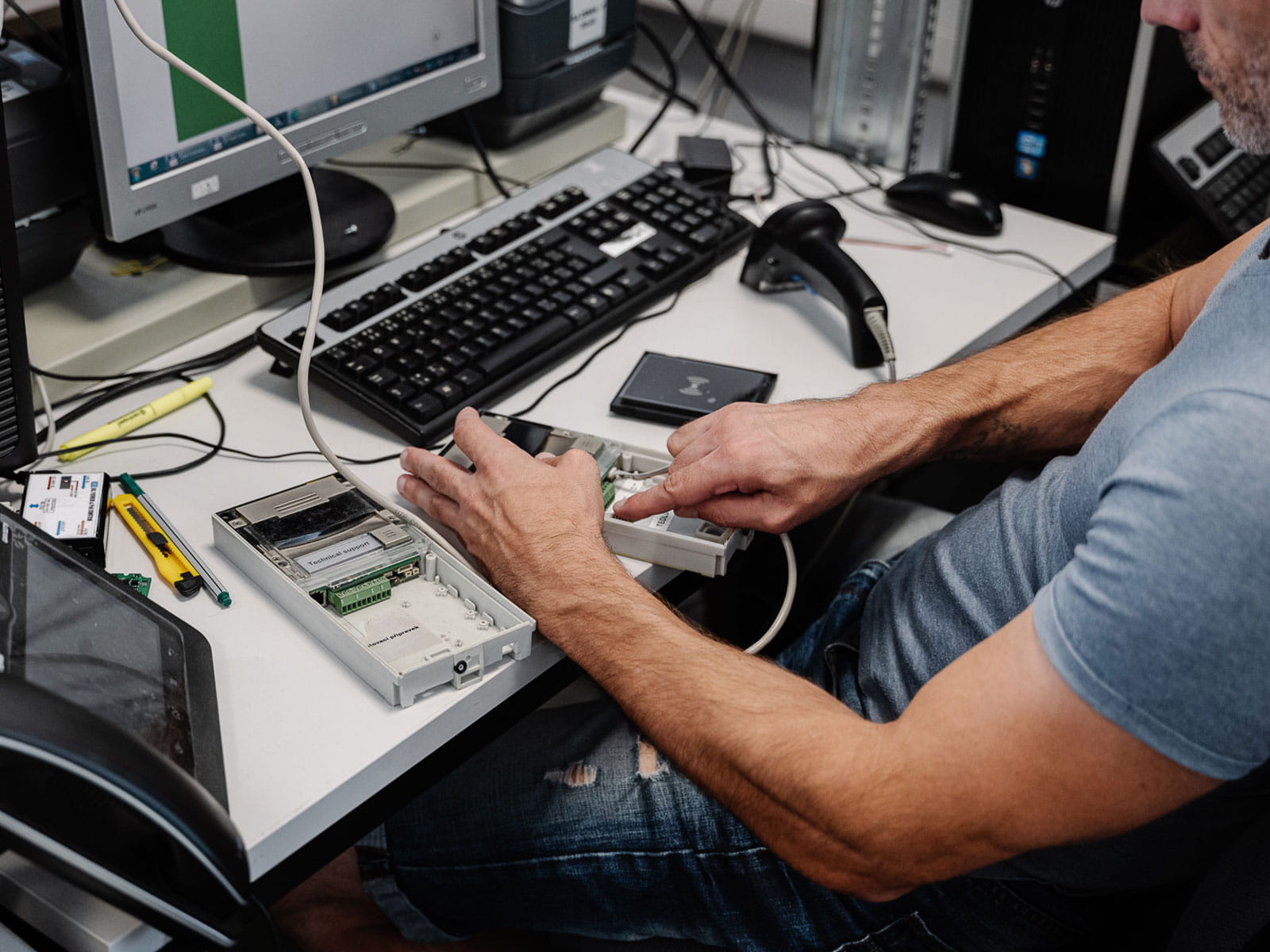 Eine Person, die an den internen Komponenten eines Computergeräts an einem Bürotisch arbeitet.