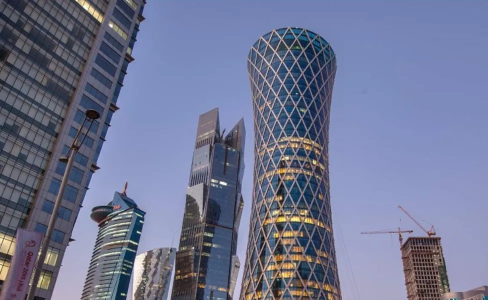 Low-angle view of modern, illuminated skyscrapers, including a distinctive lattice-covered tower.
