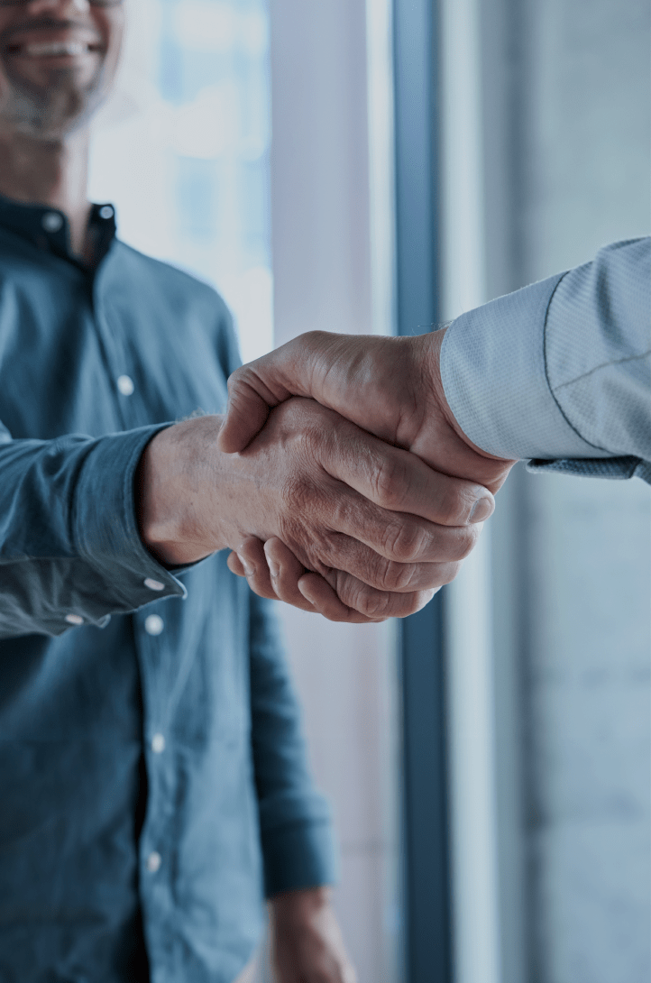Close-up van twee mensen in zakelijke kleding die een handdruk geven, wat overeenstemming of partnerschap symboliseert.