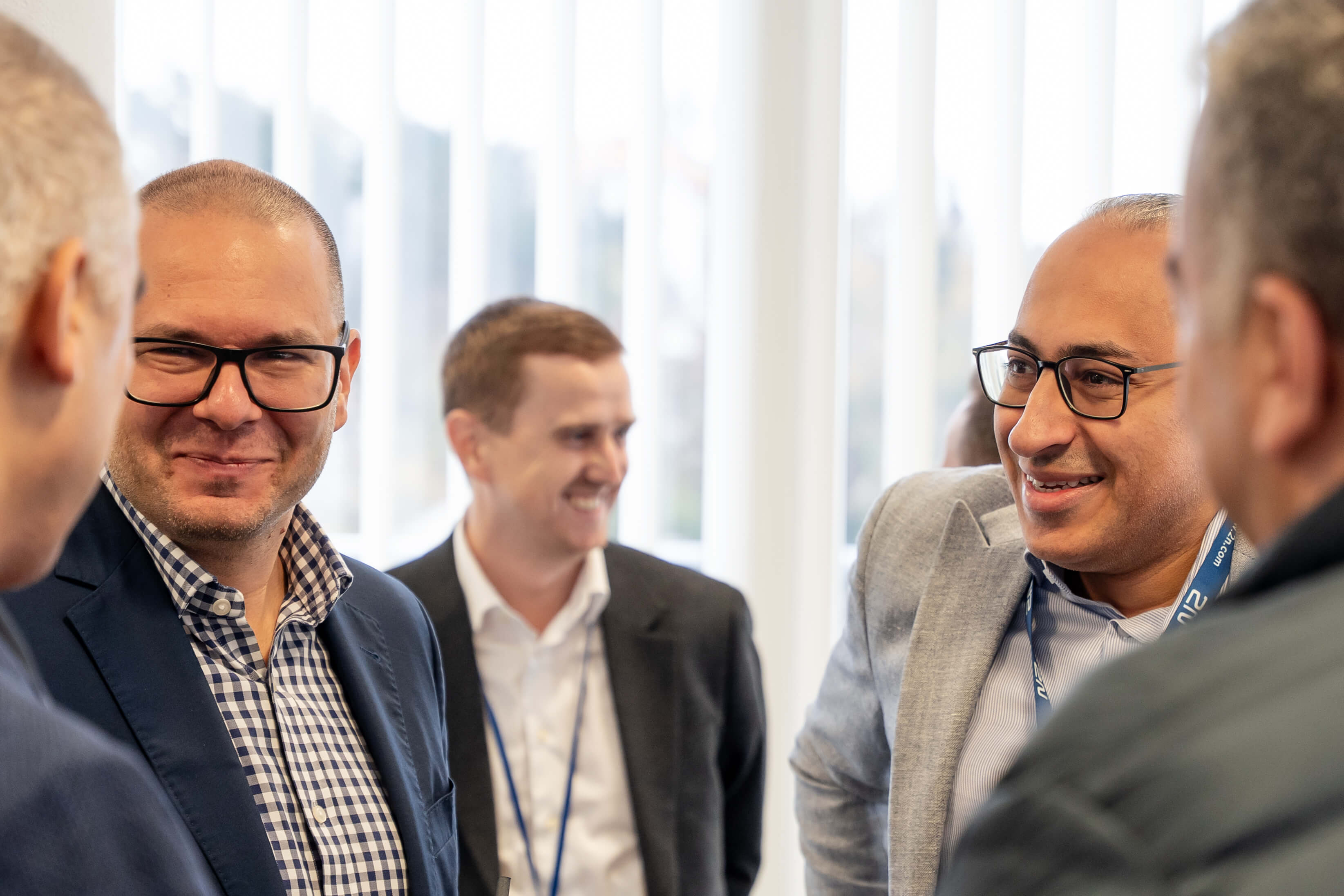 A close-up of a diverse group of three professional men smiling and chatting at an event.