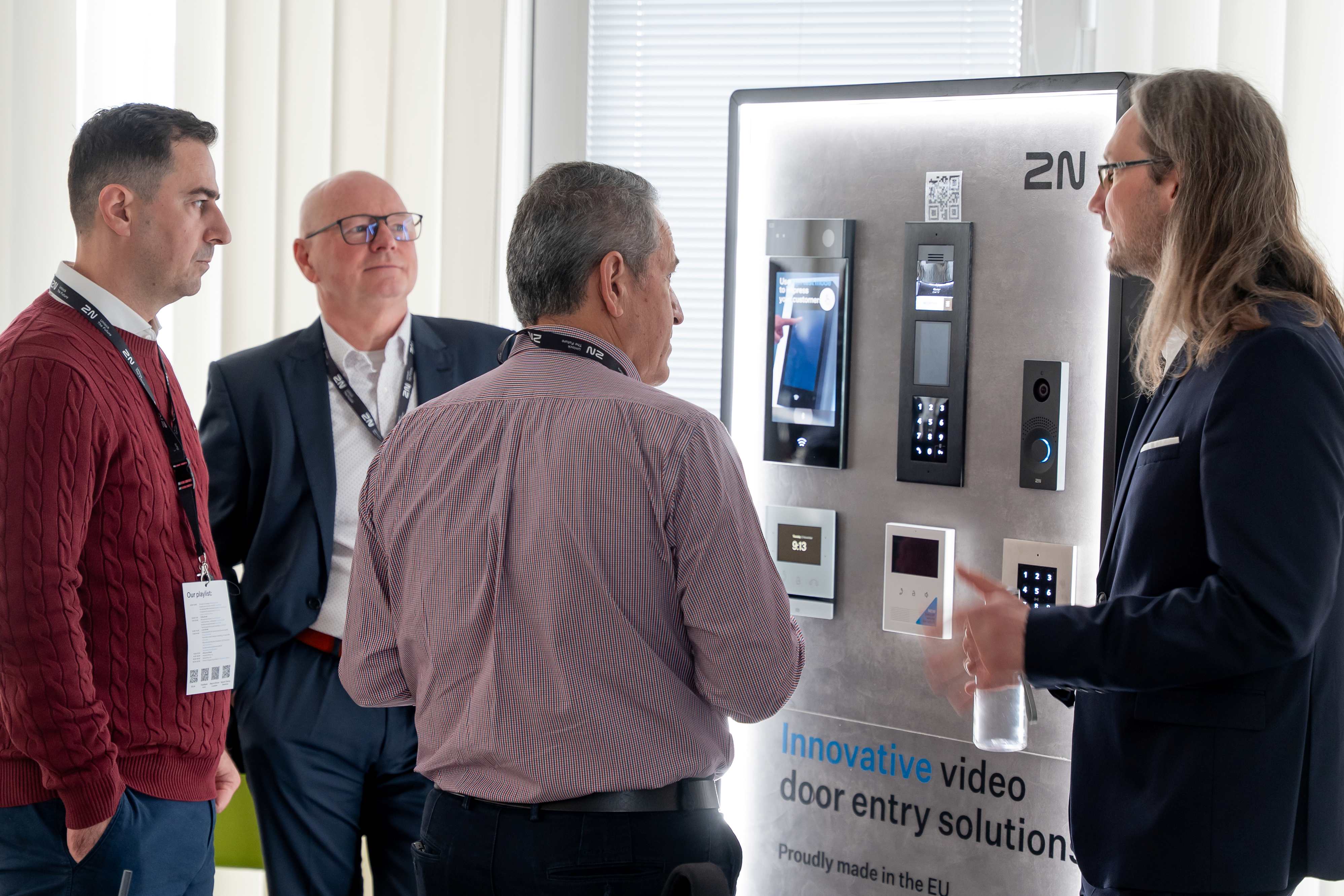 Four men discussing a 2N video door entry solution display at a professional event.