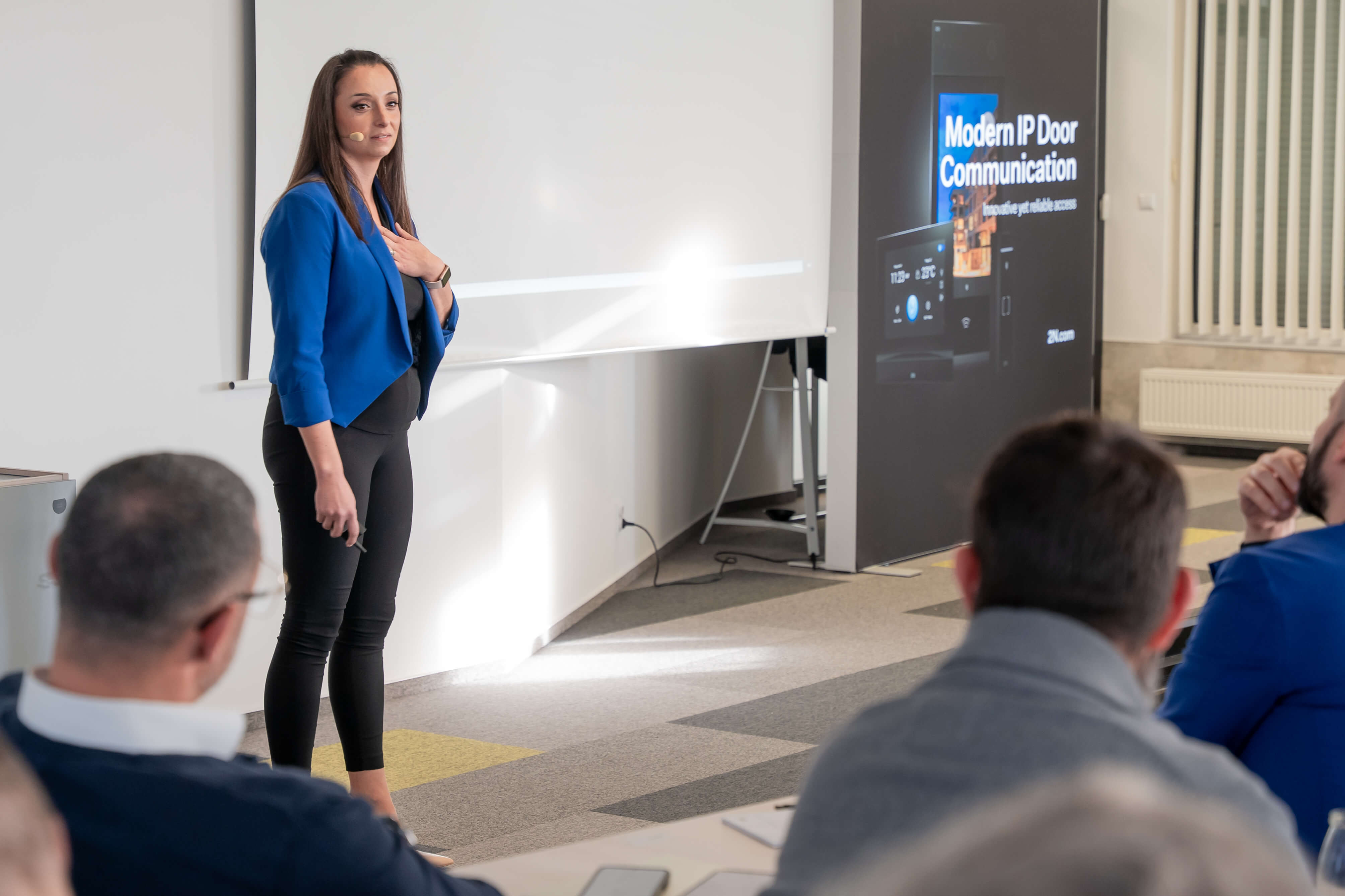 A female speaker in a blue jacket presents on stage near a "Modern IP Door Communication" banner.