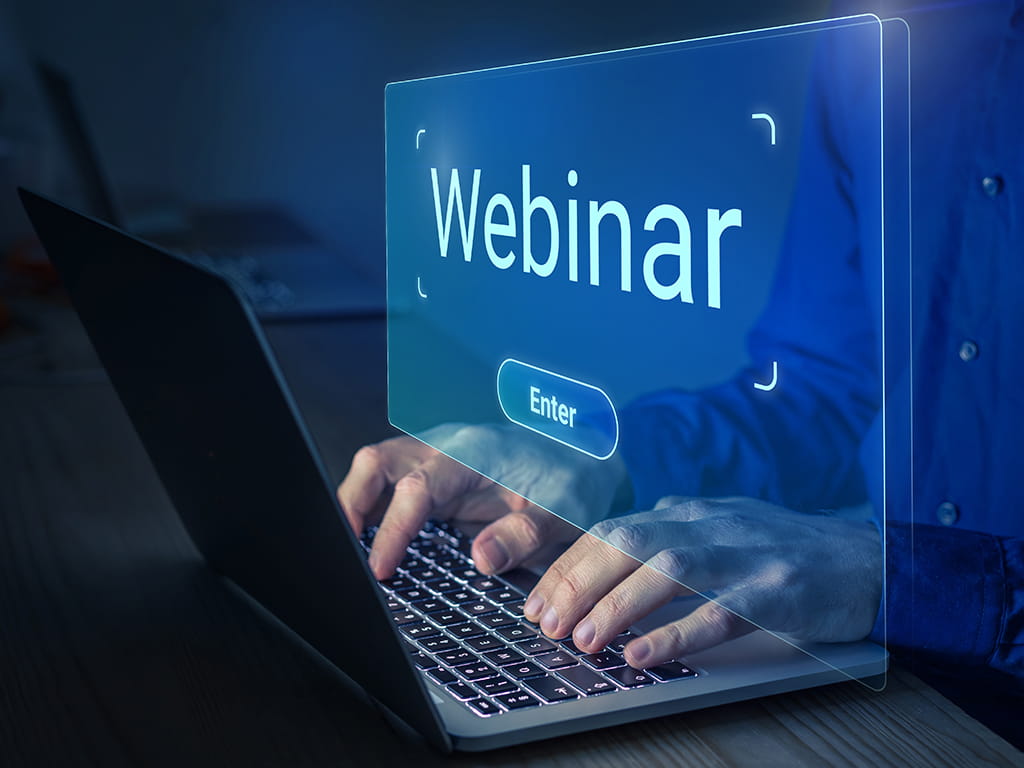 Personne tapant sur un ordinateur portable avec un écran numérique lumineux superposé affichant le mot "Webinaire" et un bouton "Entrer".