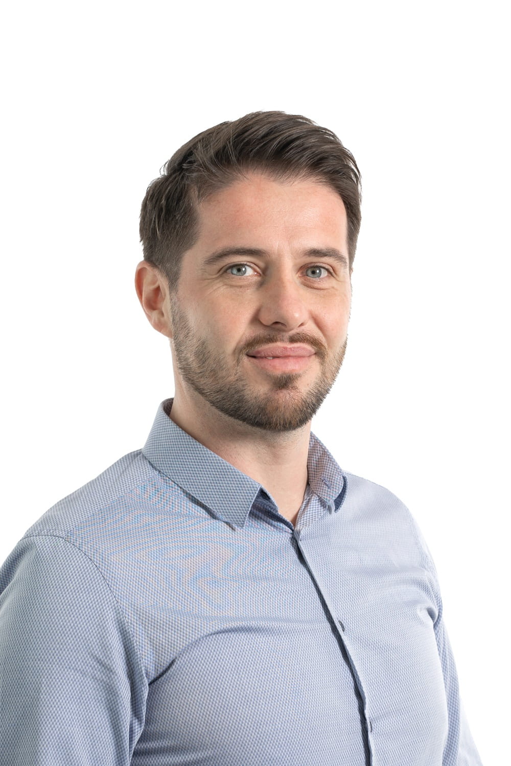 Photo pro d'un mec aux cheveux courts foncés et à la barbe, avec une chemise boutonnée bleu clair.
