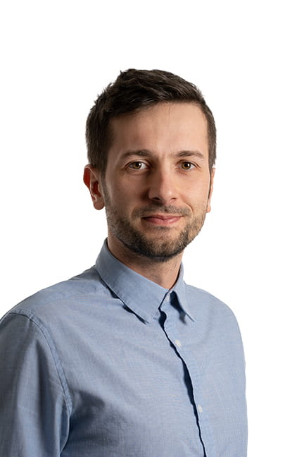 Photo professionnelle d'un homme avec des cheveux bruns courts et une barbe, portant une chemise bleue à col.