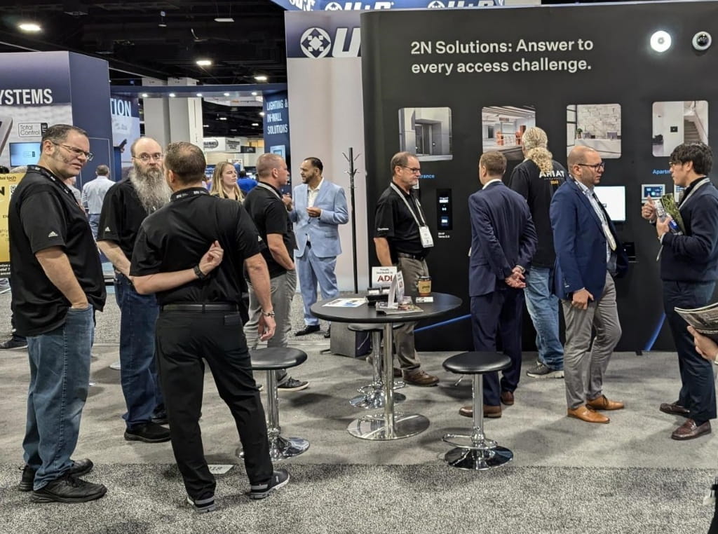 People gathered around a 2N booth at a trade show, showcasing access control solutions with product displays.