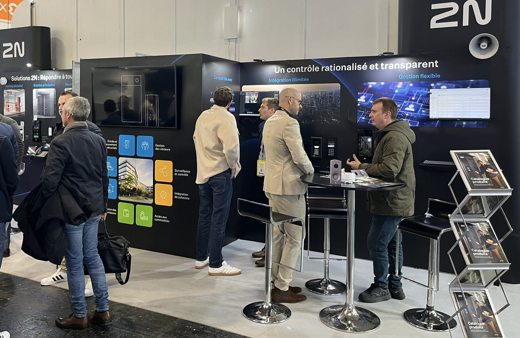 People interacting at a 2N exhibition booth featuring product displays and informational panels.