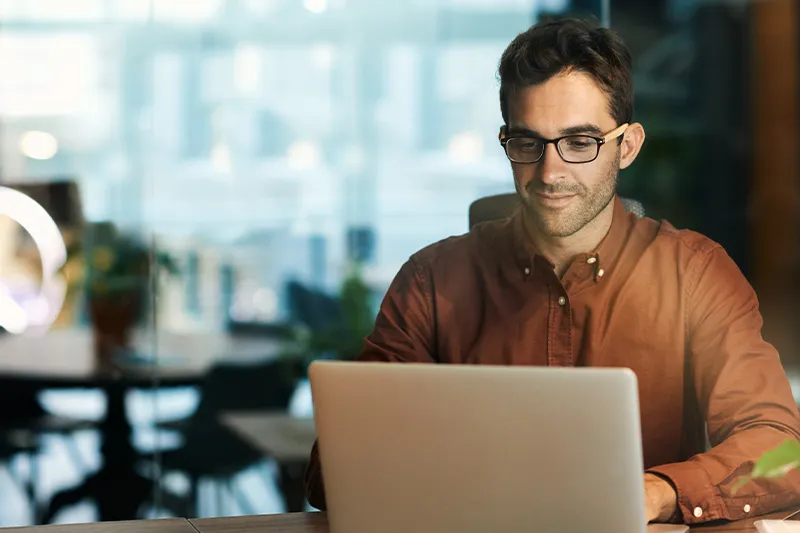 Person working on a laptop in a modern, softly lit workspace.