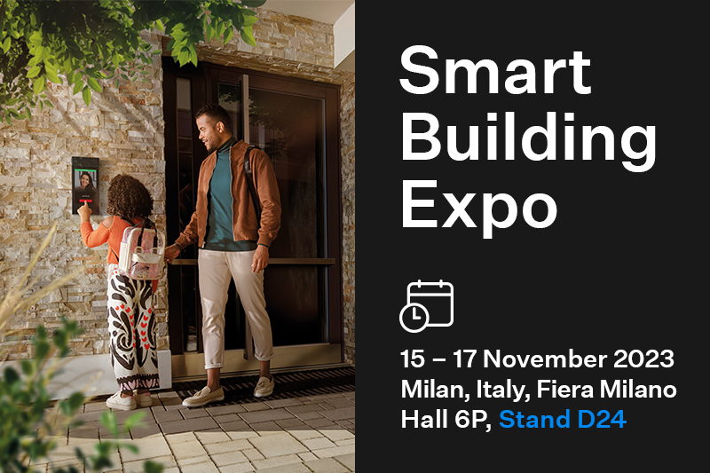 Un homme et un enfant utilisent un dispositif de contrôle d'accès à côté d'une promo pour le salon Smart Building Expo 2023 à Milan.