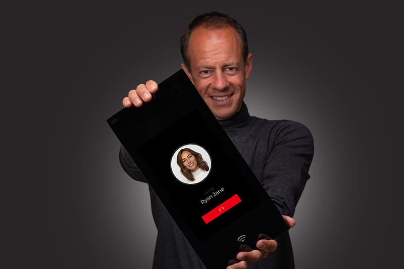 Personne tenant un appareil d'interphone vidéo intelligent affichant un écran d'appel vidéo entrant.