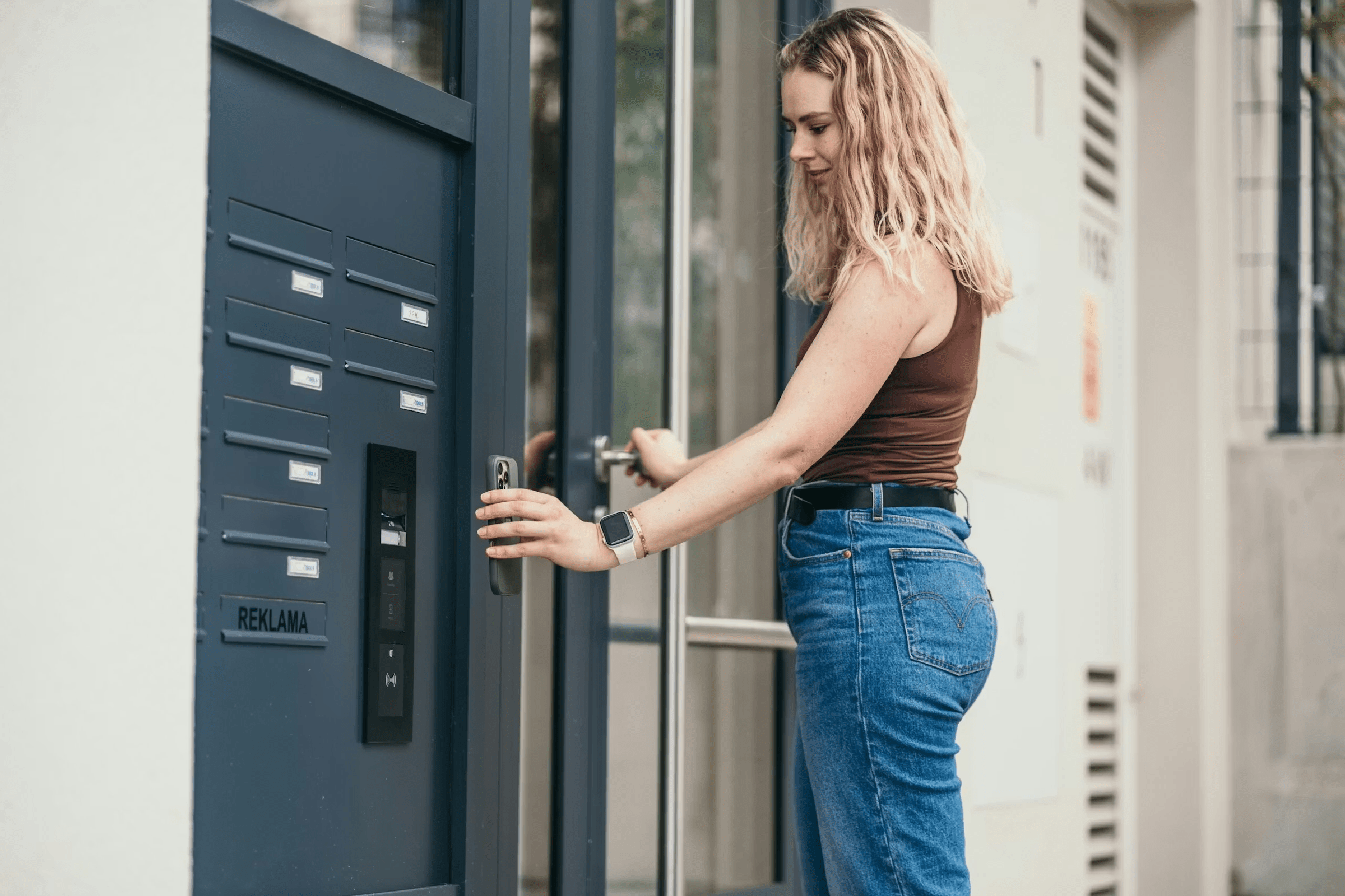 Vrouw gebruikt een 2N-toegangscontroleapparaat om de toegang deur van een woongebouw te openen.