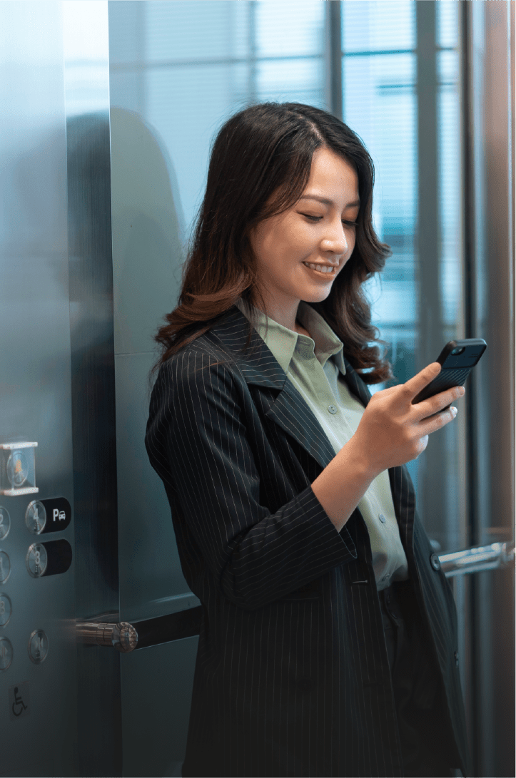 Femme debout, souriante et regardant son téléphone