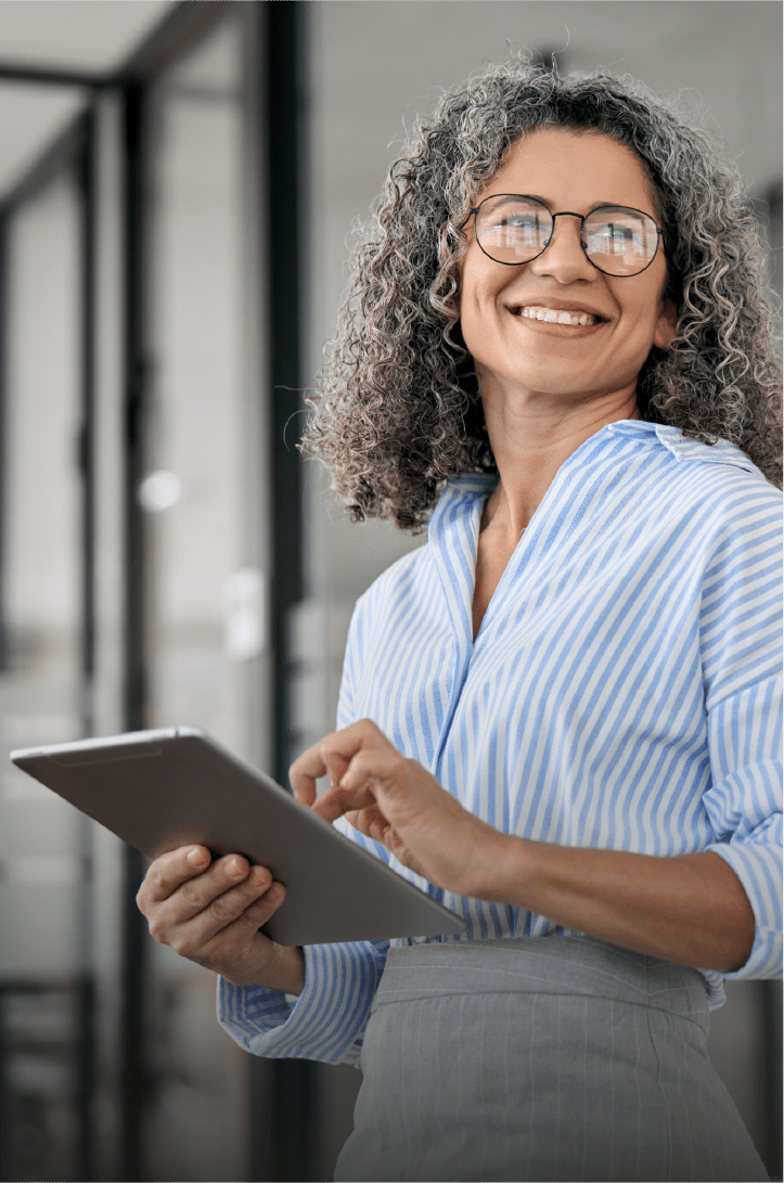 Une femme souriante se tenant debout et tenant sa tablette pour le contrôle à distance.