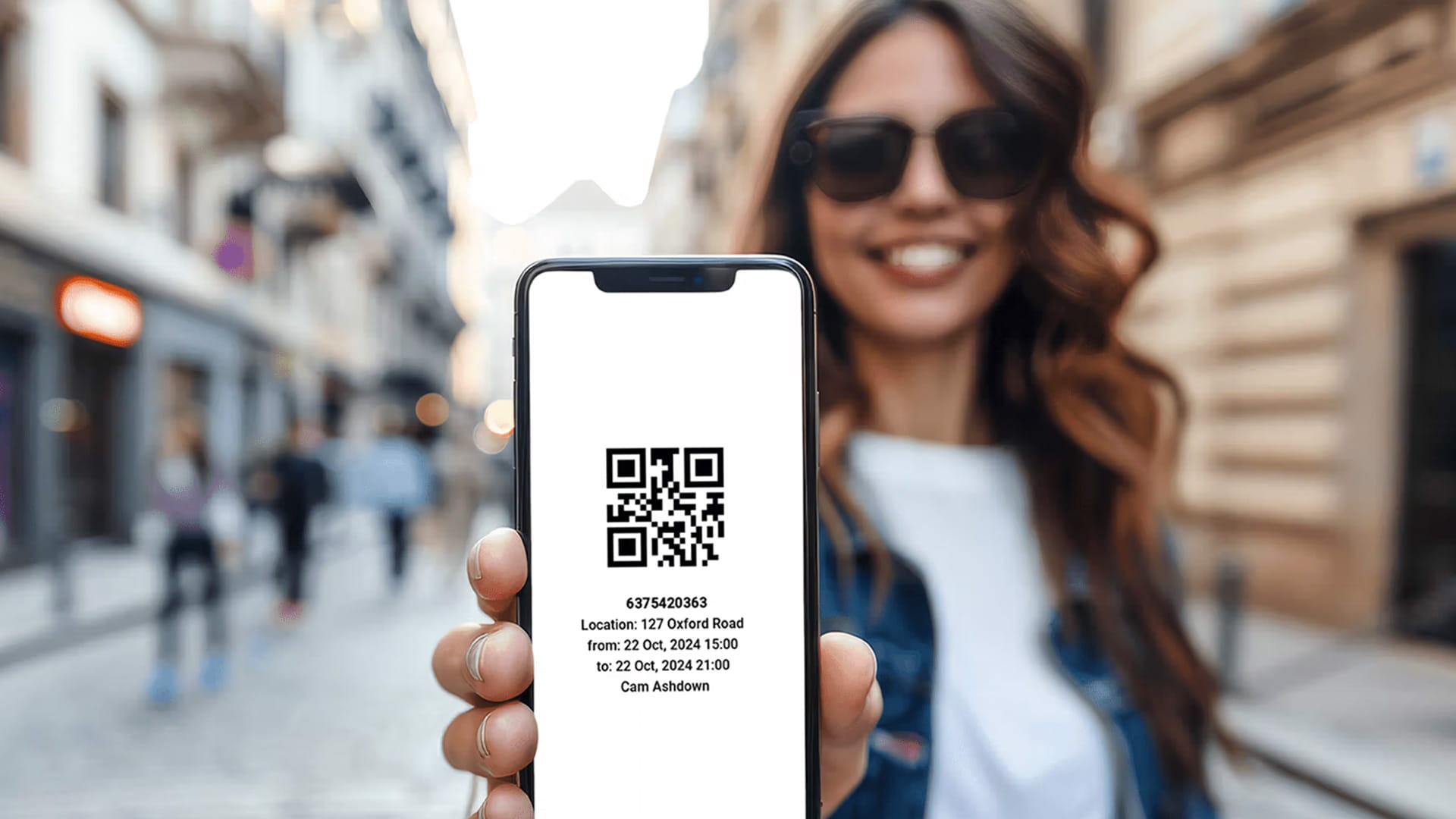 Persona che tiene uno smartphone che mostra un codice QR per l'autorizzazione in una strada della città.