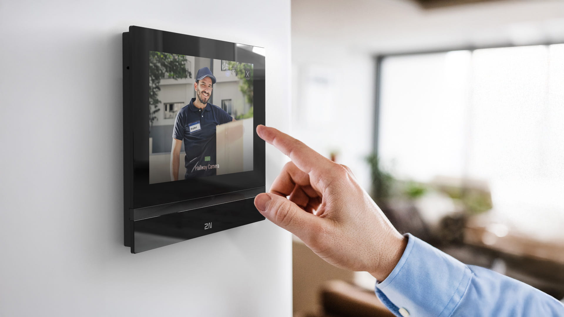 アパートの住人が、壁に取り付けられた上品な黒の2N Indoor Talkを使って配達員と会話している。