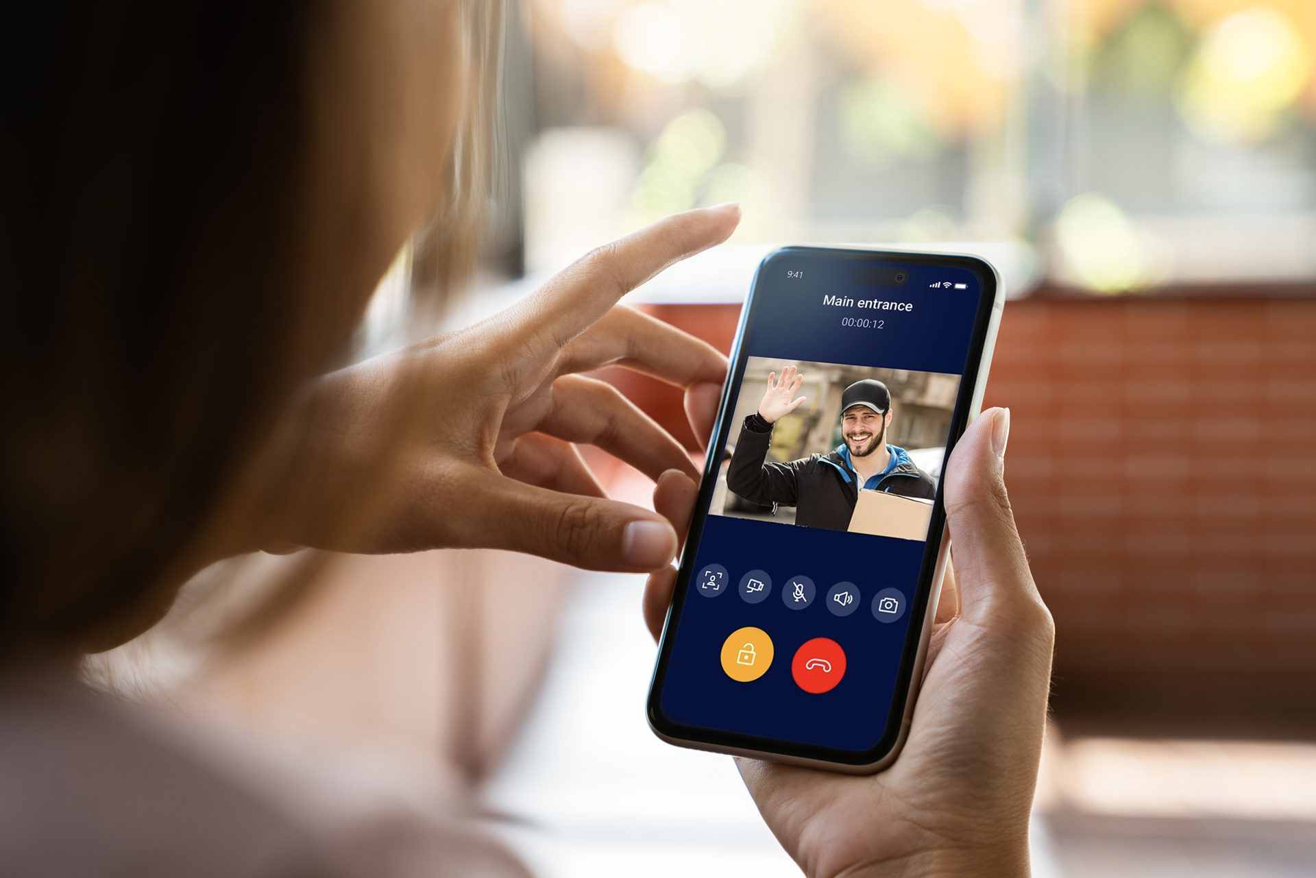 Je ziet een smartphone met een videogesprek met een bezorger die bij een deur staat.