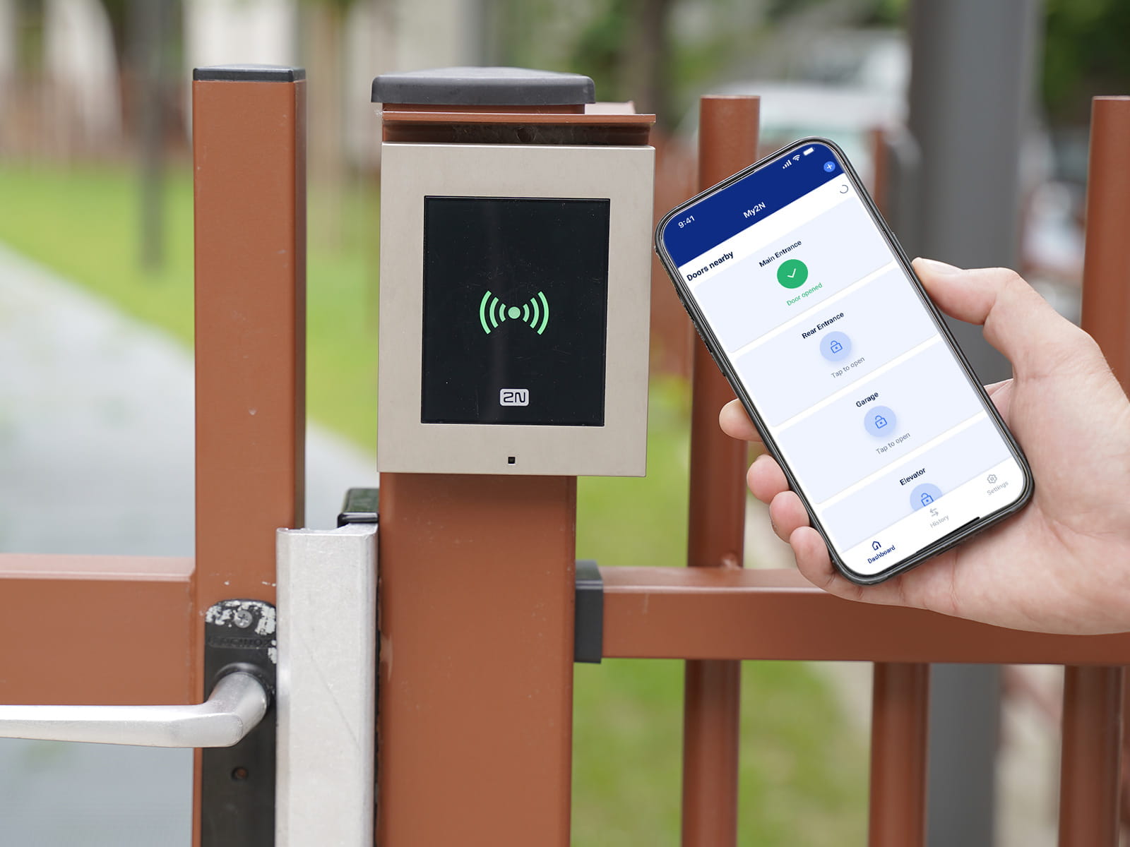 Smartphone a mostrar uma aplicação de controlo de acesso perto de um leitor RFID montado na porta com indicador verde.