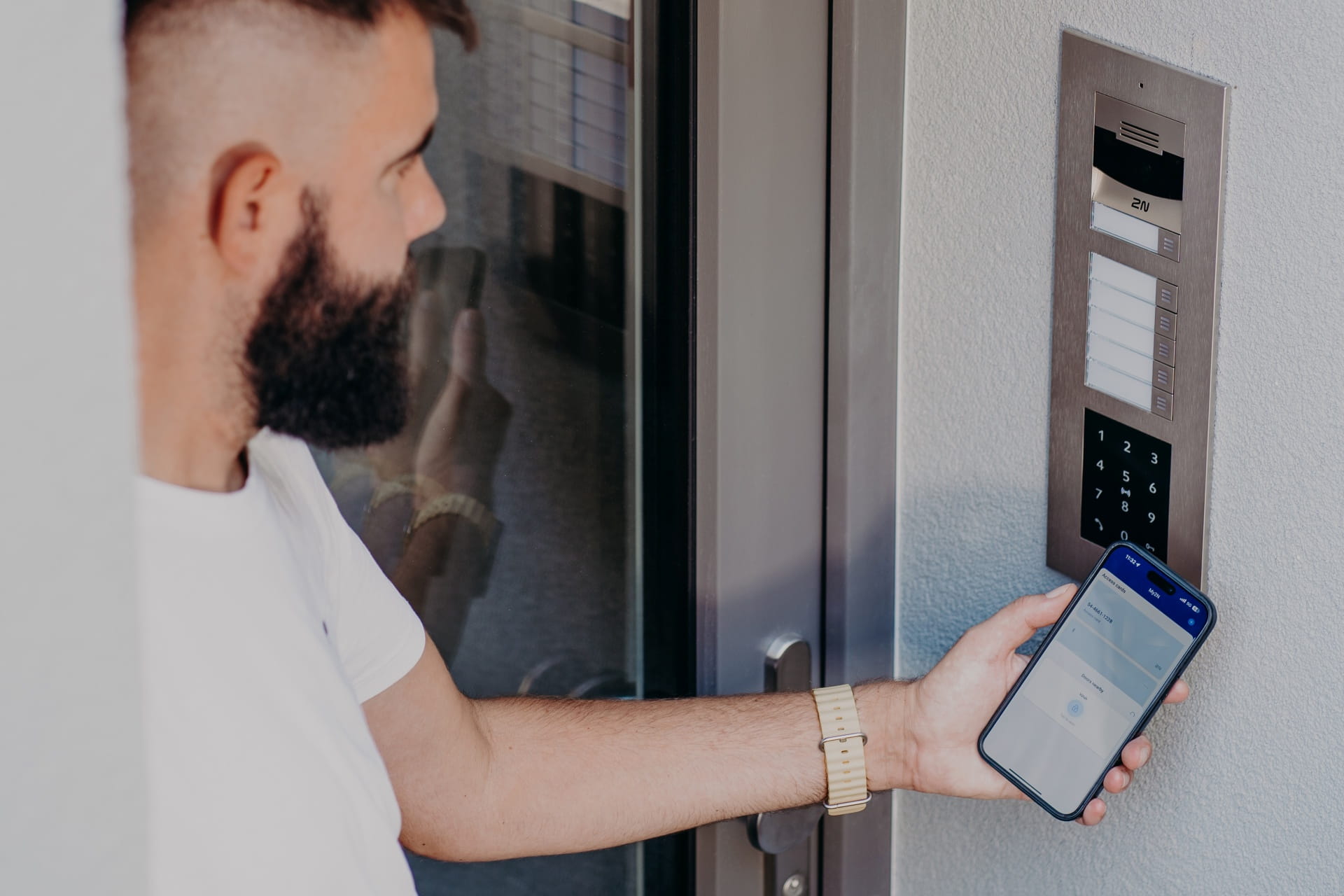 Personne utilisant un smartphone pour déverrouiller une porte via un système de contrôle d'accès par clavier.