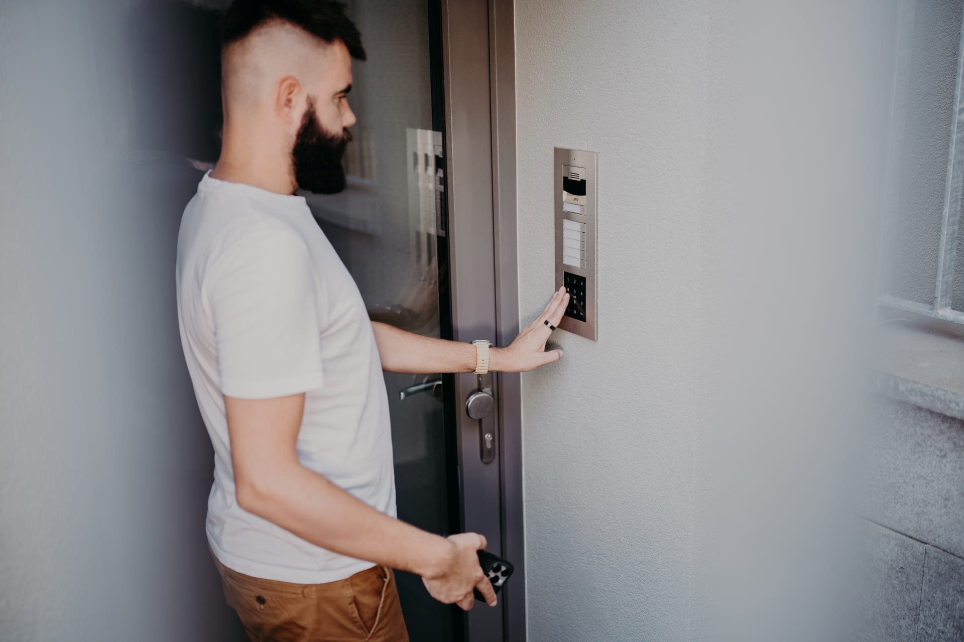  Personne utilisant un système de contrôle d'accès par clavier pour déverrouiller une porte tout en tenant des clés.