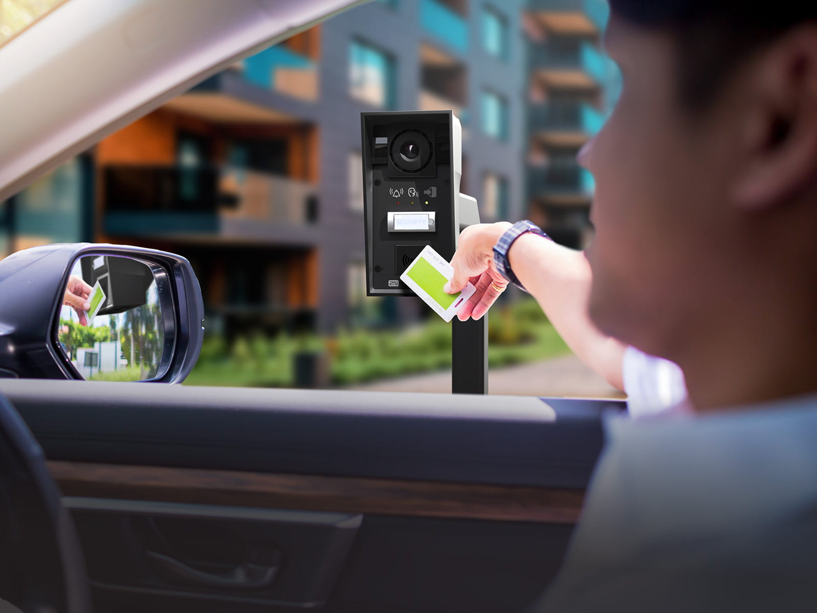 Person in a car holding an access card near a black outdoor reader at a gated residential entrance.