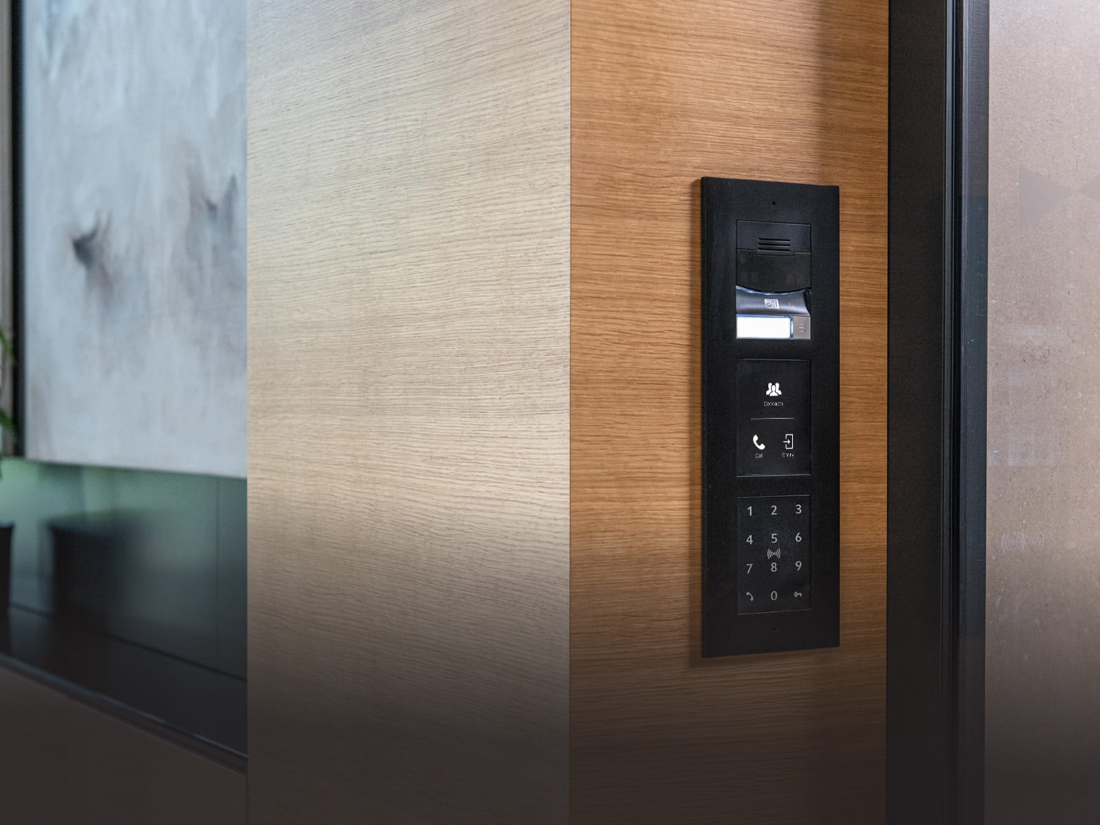 Wall-mounted intercom and access control device with keypad and camera on a wooden panel near a doorway.