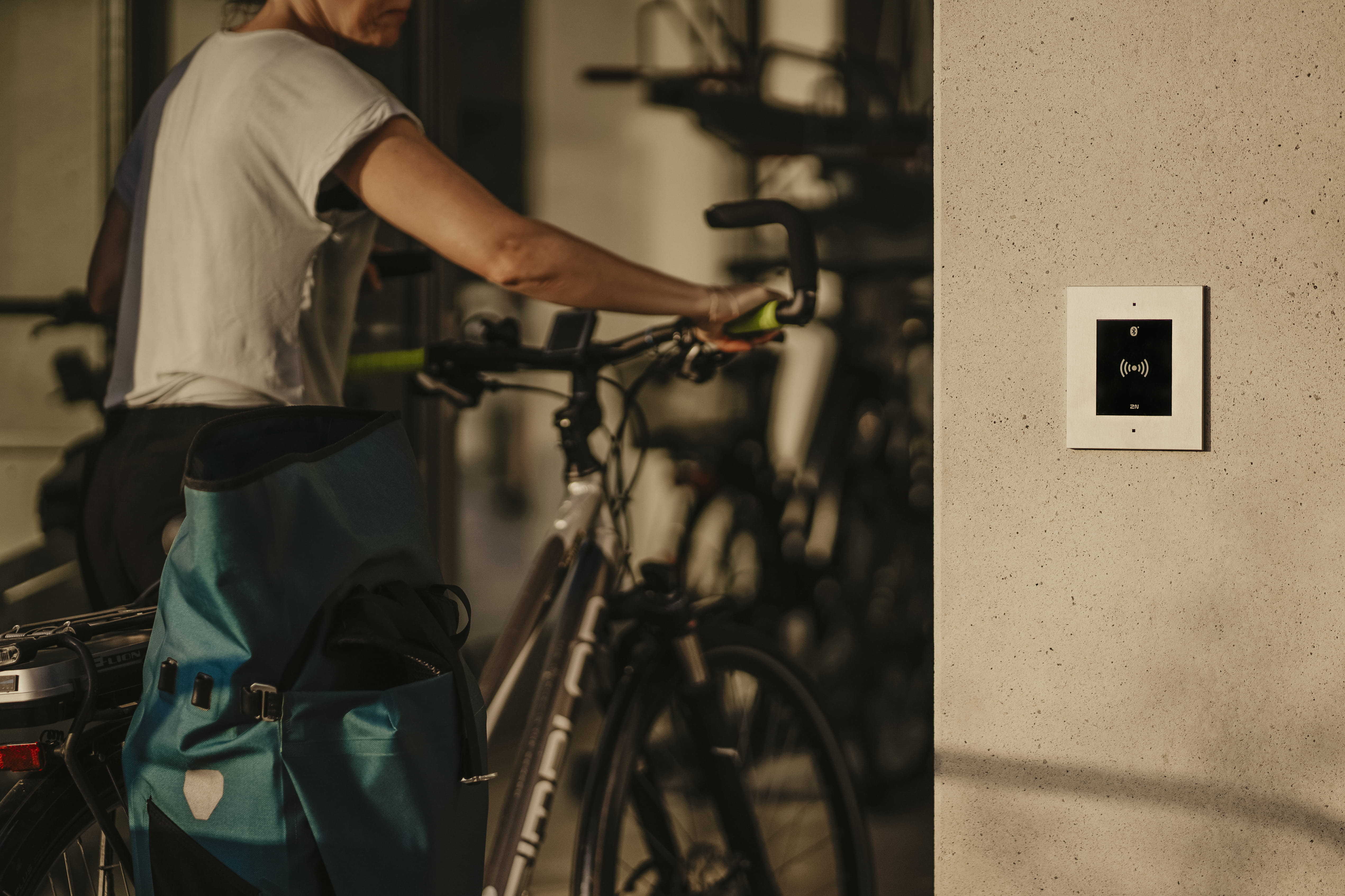 Quelqu'un qui gare son vélo près d'un panneau de contrôle d'accès fixé au mur dans un local à vélos moderne.