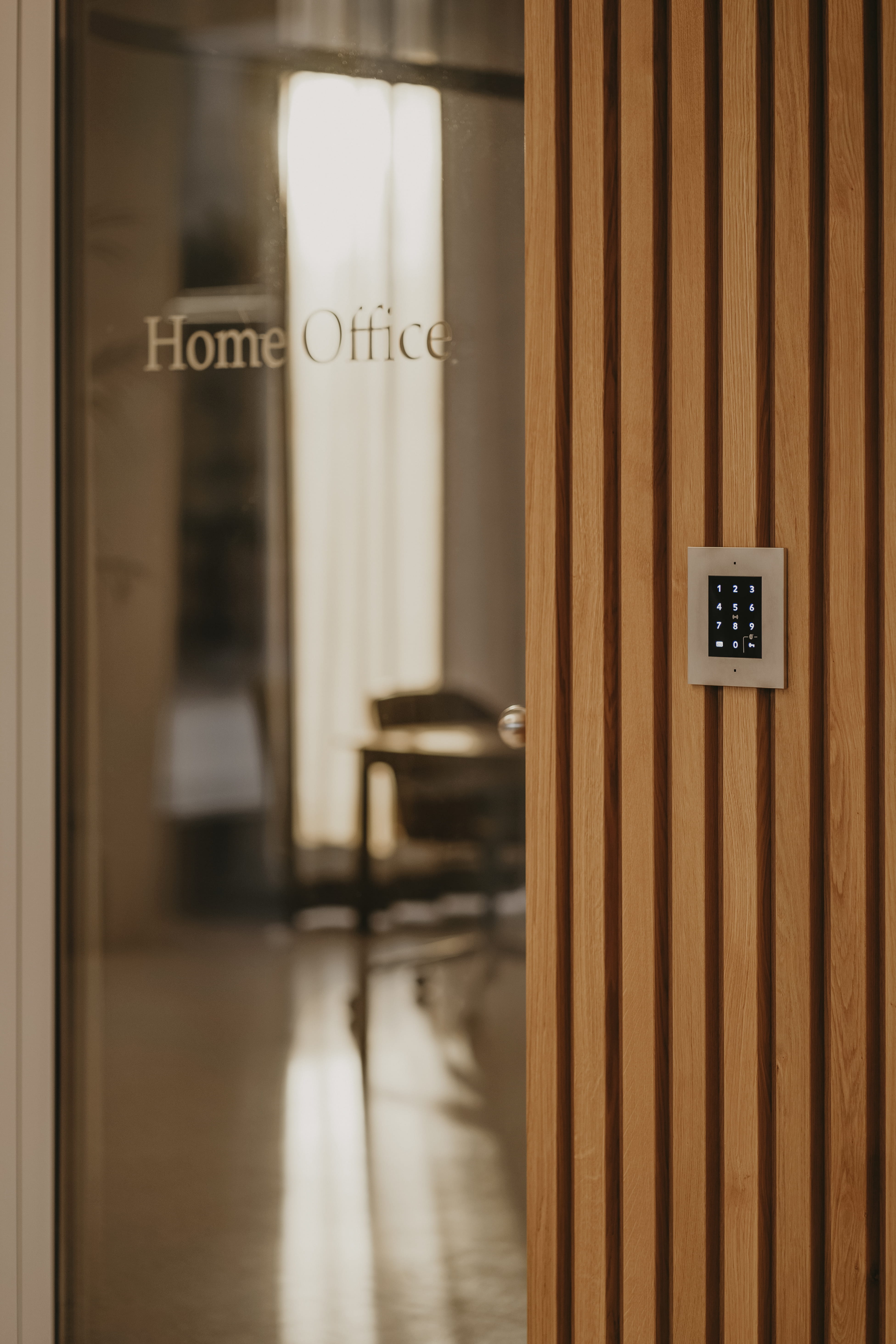 Porte en verre avec l'inscription « Home Office », boiseries et système d'accès par clavier à côté.
