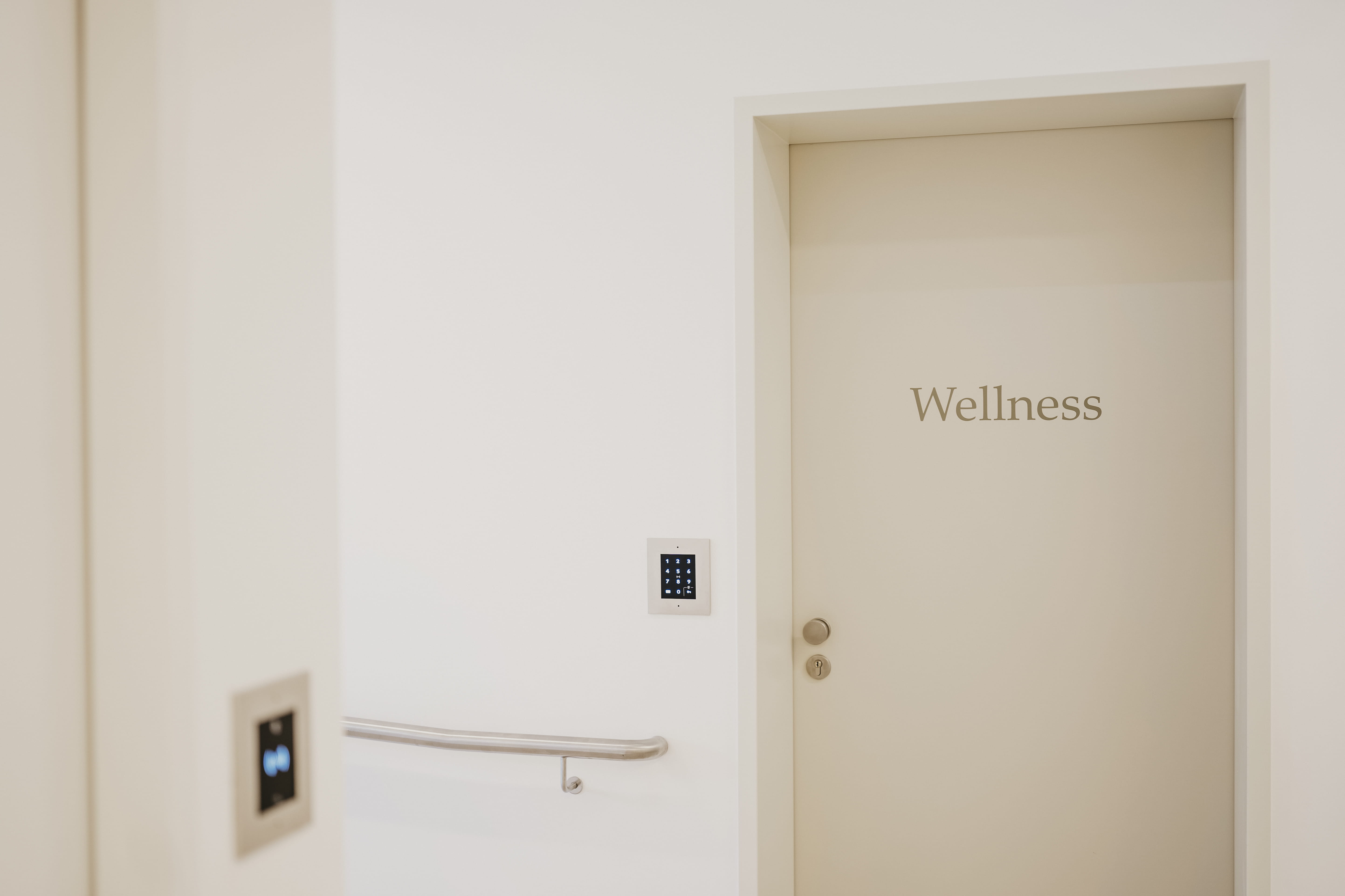 Porte fermée étiquetée « Bien-être » dans un couloir lumineux avec deux panneaux de contrôle d'accès muraux.