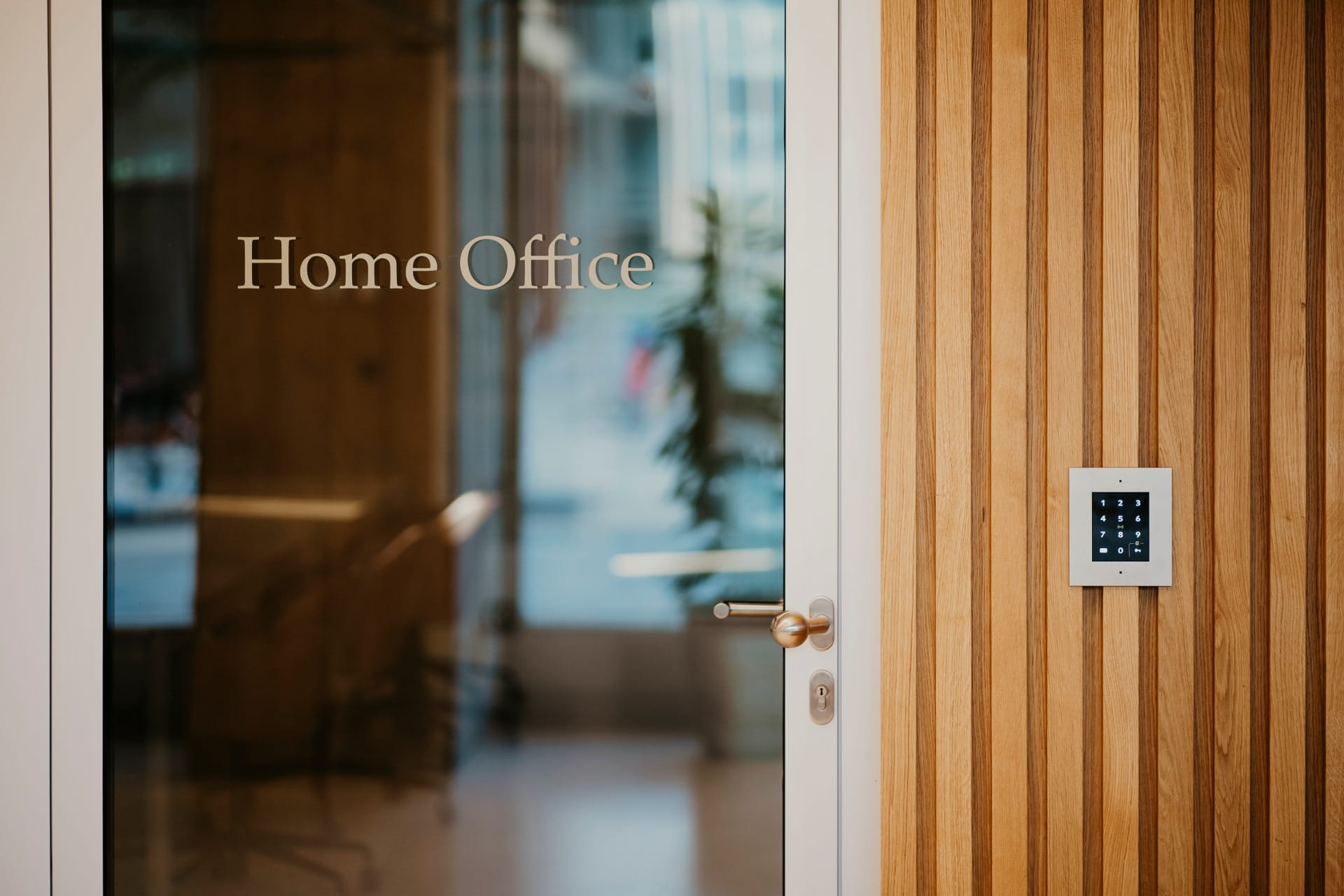 Porte en verre étiquetée « Bureau à domicile » à côté d'un mur en bois avec un panneau de contrôle d'accès monté.