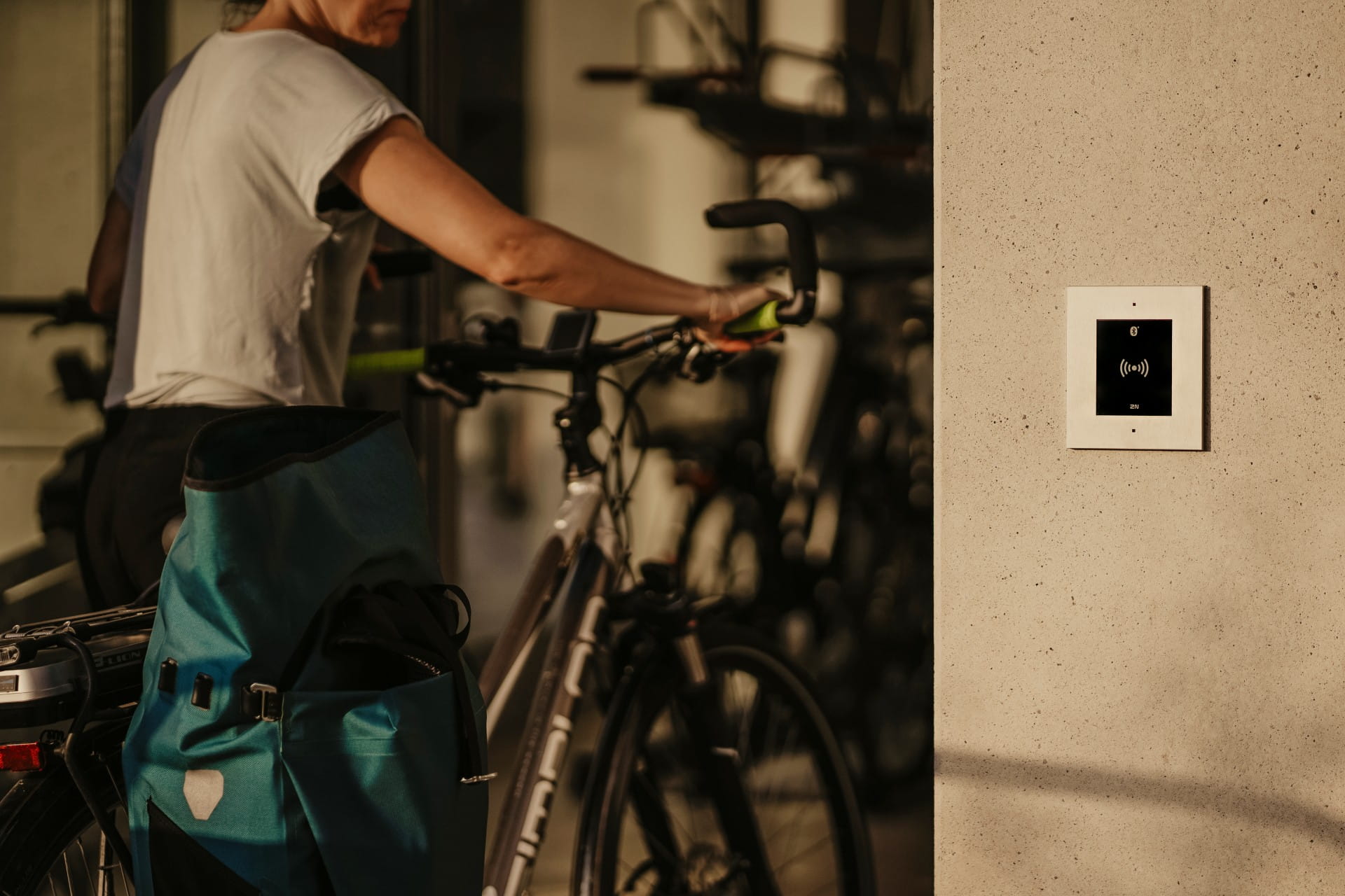Personne avec un vélo près d'un panneau de contrôle d'accès mural dans l'entrée d'un bâtiment moderne.