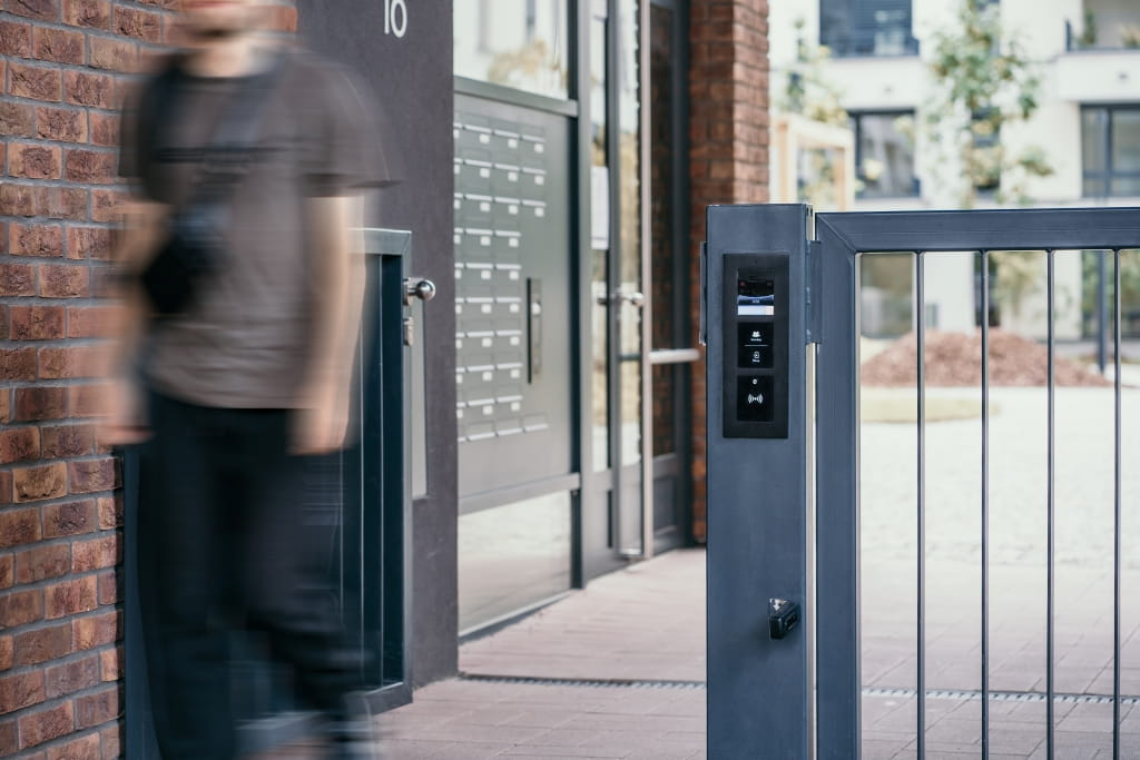 Porte moderne avec un panneau de contrôle d'accès installé sur un poteau près de l'entrée d'un immeuble d'appartements.