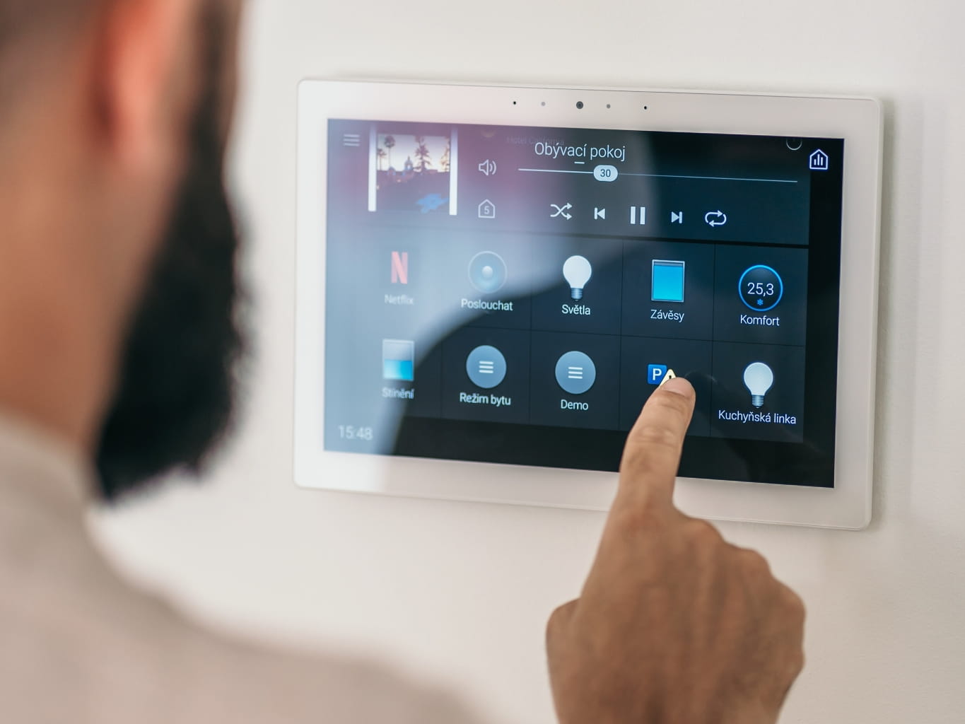 Personne utilisant un panneau de contrôle d'accès à écran tactile mural dans un intérieur moderne.
