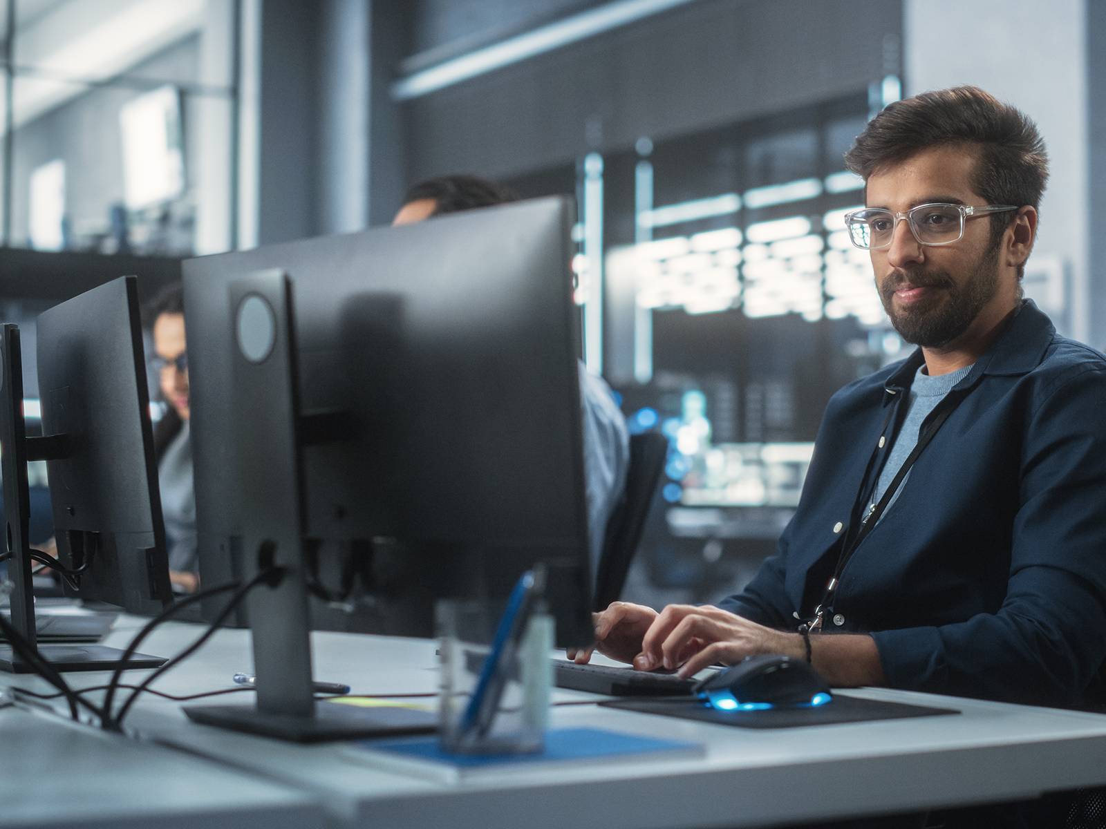 Software developer working at multiple monitors in a modern office